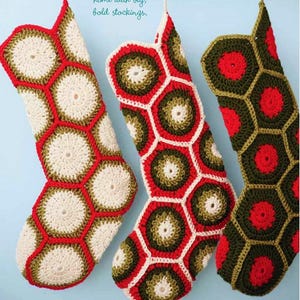 May include: Three crocheted Christmas stockings in red, green and white with a geometric pattern. The stockings are hanging on a blue background. The text "Brighten your home with big, bold stockings." is written above the stockings.