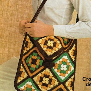 May include: A brown, green, yellow, and white crocheted shoulder bag with a square pattern. The bag is being held by a person wearing a white shirt.