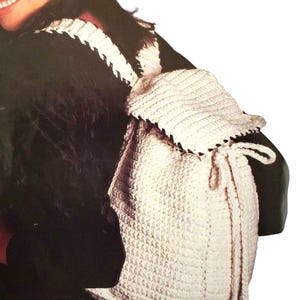 Peut inclure: Un sac à dos en crochet blanc avec une bordure noire. Le sac à dos a un rabat avec une fermeture à cordon et deux longues bretelles.