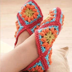 Può includere: Pantofole all'uncinetto fatte a mano con un vivace design a granny square. Le pantofole presentano una combinazione di filato rosso, arancione, blu e giallo. Un accessorio accogliente e colorato.