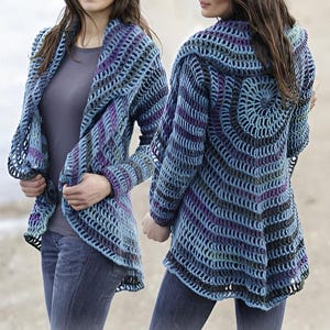 以下が含まれることがあります： フード付きの青、紫、緑のクロシェ編みカーディガン。カーディガンはゆったりとしたフィット感で、長く流れるようなデザインです。