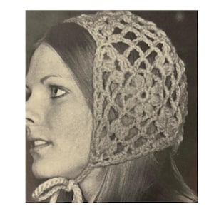 Könnte beinhalten: Ein gehäkelter Hut in hellem Beige im Vintage-Stil. Der Hut hat ein offenes Blumenmuster und wird unter dem Kinn mit einer passenden Kordel gebunden. Das Bild ist eine Nahaufnahme, die die Textur und die Details der handgefertigten Kopfbedeckung hervorhebt.