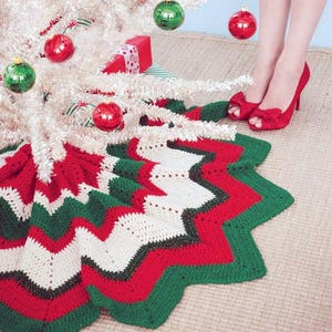May include: A crocheted Christmas tree skirt with a red, white, and green chevron pattern. The skirt is made with a thick yarn and has a scalloped edge.