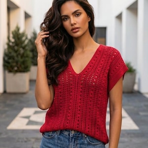 Pode incluir: Uma blusa vermelha vibrante de manga curta com um padrão intrincado de crochê aberto e decote em V, combinada com calças de ganga azuis clássicas. A peça tem um corte descontraído e um design texturizado e respirável para uso casual.
