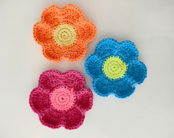 May include: Three crocheted flower coasters in orange, blue, and pink with a yellow center.
