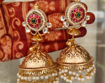 May include: A pair of gold earrings with a pink and green floral design, white pearl accents, and a dangling pearl tassel.
