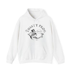 May include: White hooded sweatshirt with a black and white illustration of a frog wearing a top hat and holding a glass. The text "the TOASTY FROG" is printed in a circular arc above the frog. The text "Cheer!" is printed below the frog.