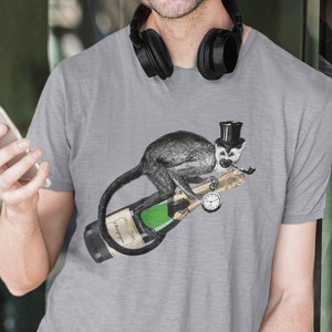 Puede incluir: Una camiseta gris con un gráfico de un mono con un sombrero de copa y sosteniendo una pipa, sentado en una botella de champán con un reloj de bolsillo.