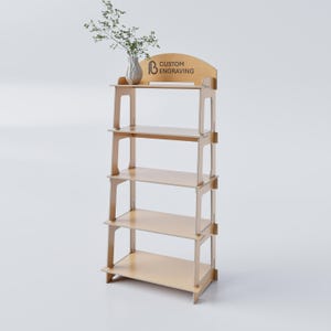 Peut inclure: Étagère d'exposition en bois clair à quatre niveaux. Le haut de l'étagère a un design incurvé avec le texte "CUSTOM ENGRAVING". Un vase avec de la verdure est posé sur l'étagère supérieure. L'étagère est en bois clair.
