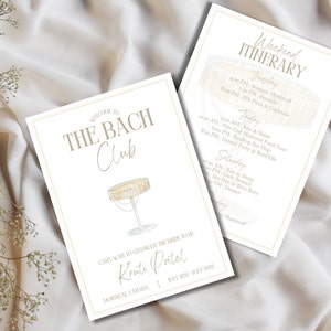 May include: A white card with gold text and a gold border. The card says "Welcome to The Bach Club" and features a drawing of a champagne flute. The card also says "Can't wait to celebrate the bride to be Kruti Patel" and "Montreal, Canada | July 20th - July 22nd". A second white card with gold text and a gold border says "Weekend Itinerary" and lists the events for a bachelorette party. The cards are on a white fabric background.