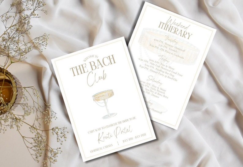 May include: A white card with gold text and a gold border. The card says "Welcome to The Bach Club" and features a drawing of a champagne flute. The card also says "Can't wait to celebrate the bride to be Kruti Patel" and "Montreal, Canada | July 20th - July 22nd". A second white card with gold text and a gold border says "Weekend Itinerary" and lists the events for a bachelorette party. The cards are on a white fabric background.