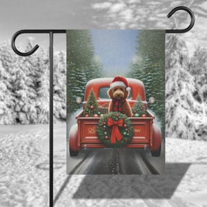 May include: A red pickup truck with a Christmas wreath in the bed. A brown dog wearing a Santa hat is sitting in the bed of the truck. The truck is driving down a snowy road.