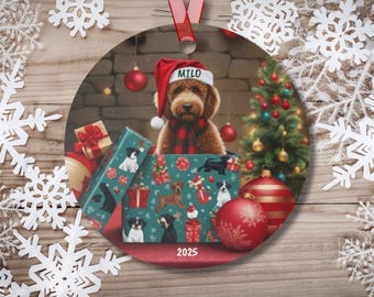 May include: Round Christmas ornament featuring a dog wearing a Santa hat with the name "Milo". The ornament has a festive design with a Christmas tree, presents, and the year "2025". The dog is inside a gift box with images of other dogs.