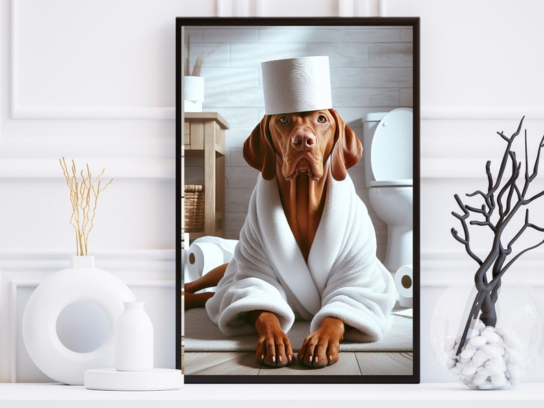 May include: A brown and white dog wearing a white bathrobe and a toilet paper roll hat. The dog is sitting on a white bathroom floor with a toilet in the background.