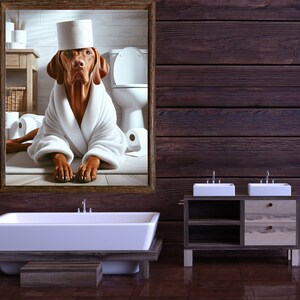May include: A framed picture of a dog wearing a white bathrobe and a toilet paper roll on its head. The dog is sitting in a bathroom with a toilet and other toilet paper rolls in the background. The picture is hanging on a dark wood wall with a white bathtub and a double sink vanity in the foreground.