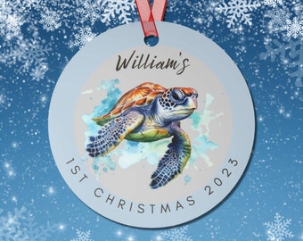 May include: A round, silver Christmas ornament with a watercolor painting of a sea turtle. The ornament has the text "William's 1st Christmas 2023" around the edge.