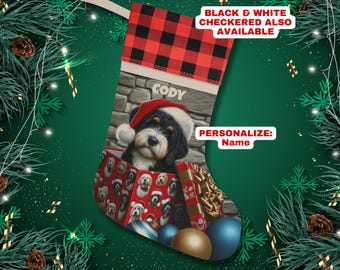May include: Personalized Christmas stocking featuring a dog wearing a Santa hat and surrounded by presents and ornaments. The stocking is red and black plaid with the name "Cody" embroidered on it. Black and white checkered stocking also available.