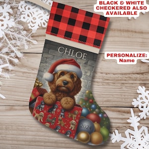 May include: Personalized Christmas stocking with a red and black buffalo plaid cuff. The stocking features a painting of a dog wearing a Santa hat and holding a gift box. The stocking is personalized with the name "Chloe".