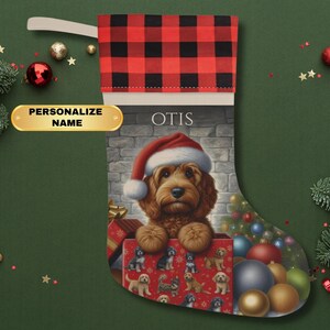 May include: A personalized Christmas stocking with a red and black buffalo plaid cuff. The stocking features a cute dog wearing a Santa hat and surrounded by Christmas ornaments. The name "OTIS" is printed on the stocking.