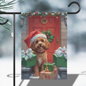 May include: A Christmas-themed garden flag featuring a brown and white dog wearing a red Santa hat and standing in front of a red door with presents. The dog is smiling and looking at the viewer.