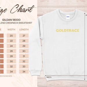Op de afbeelding: Maattabel voor een Gildan 18000 heavy blend crewneck sweatshirt. De tabel toont de breedte en lengte in inches voor maten S tot en met 5XL. De tekst "GOLDTRACE" is in goud gedrukt op een wit sweatshirt.