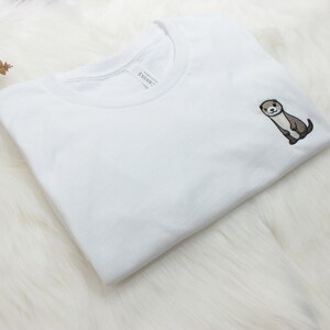 Op de afbeelding: Wit T-shirt met een kleine geborduurde otter op de linker borst.