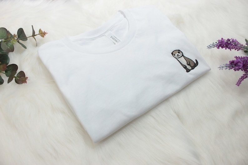 Op de afbeelding: Wit T-shirt met een kleine geborduurde otter op de linker borst.