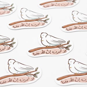 May include: White dove stickers perched on brown branches, each with Arabic text. The stickers have a light pink background and a white border. The image is a close-up shot of multiple stickers.