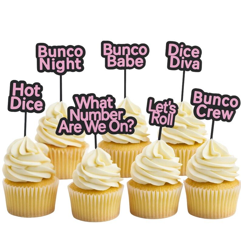 May include: Eight cupcakes with white frosting and yellow cake. Each cupcake has a black pick with a pink and white phrase: "Bunco Night", "Bunco Babe", "Dice Diva", "Hot Dice", "What Number Are We On?", "Let's Roll", and "Bunco Crew".