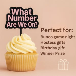 May include: A cupcake with yellow frosting and a black sign that reads "What Number Are We On?" in pink letters. The sign is on a black stick. The text "Perfect for: Bunco game night, Hostess gifts, Birthday gift, Winner Prize" is also visible.