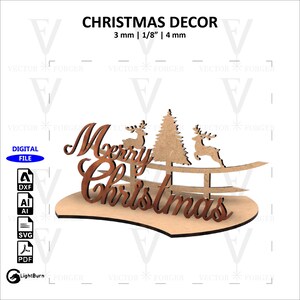Pode incluir: Uma decoração de Natal de madeira com as palavras "Merry Christmas" em uma fonte festiva. A decoração inclui duas renas, uma árvore de Natal e uma cerca. A decoração tem uma espessura de 3 mm, 1/8 de polegada ou 4 mm.