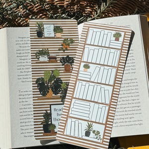 May include: Two printable bookmark designs featuring a bookshelf with books and plants. The first bookmark has a striped background with the text "Just one more page". The second bookmark has a striped background with the text "Read live think".