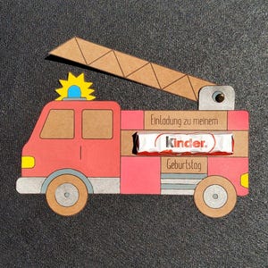 May include: A red fire truck invitation with a Kinder chocolate bar inside. The invitation says "Einladung zu meinem Geburtstag" which translates to "Invitation to my birthday".
