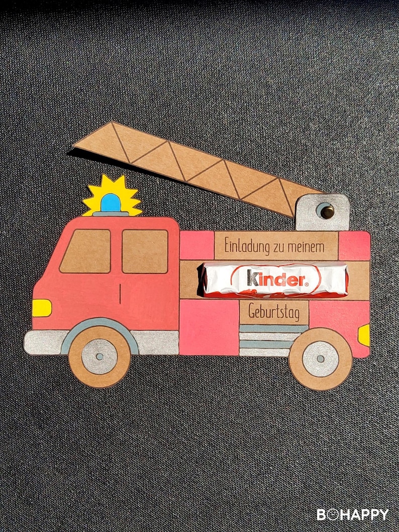 May include: A red fire truck invitation with a Kinder chocolate bar inside. The invitation says "Einladung zu meinem Geburtstag" which translates to "Invitation to my birthday".