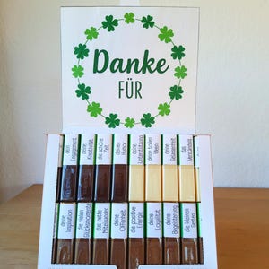 May include: A white box of assorted mousse chocolates with a green shamrock wreath and the German words "Danke F&uuml;r" on the lid. The chocolates have various German words on their wrappers.