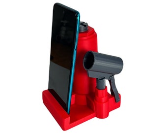 Puede incluir: Un soporte para teléfono impreso en 3D de color rojo y negro con un soporte para teléfono integrado y una pequeña botella de spray. El soporte para teléfono está diseñado para sostener un teléfono inteligente en posición vertical.