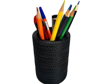 May include: A black tire-shaped pencil holder with a variety of colored pencils and pens inside.