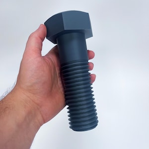 Könnte beinhalten: Ein großer, grauer Metallbolzen mit sechseckigem Kopf und einem Gewinde.