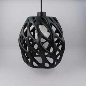 Pode incluir: Uma luminária pendente preta com um design único, orgânico e intrincado. A luminária é feita de um material preto de tecido aberto que se assemelha a uma teia de aranha ou uma rede.