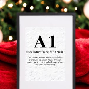 Puede incluir: Un marco de fotos negro con un paspartú blanco y el texto "A1 Black Picture Frame & A2 Mount" e instrucciones para quitar la película protectora del plexiglás antes de usar.