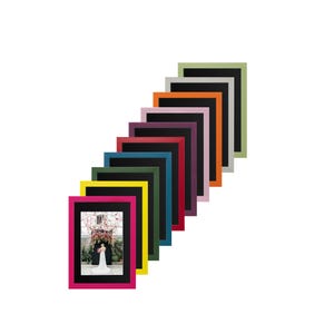 May include: A set of 10 picture frames in various colours, including pink, red, orange, yellow, green, blue, purple, black, grey, and sage green. The frames are arranged in a staggered pattern, with the smallest frame at the bottom and the largest frame at the top. Each frame has a black mount and a white background.