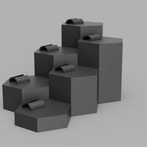 May include: A gray, stepped display stand with six hexagonal platforms of varying heights. Each platform holds a small, curved, dark gray object, possibly for displaying jewelry or small items. The background is a solid gray.