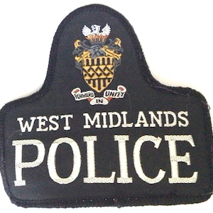 Puede incluir: Parche bordado negro con las palabras "WEST MIDLANDS POLICE" en blanco. El parche presenta un escudo con un blasón y las palabras "FORWARD IN UNITY".