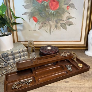 May include: A wooden jewelry organizer with multiple compartments and a center stand. The organizer is brown and has a smooth finish. It is filled with various jewelry pieces, including necklaces, bracelets, and earrings.