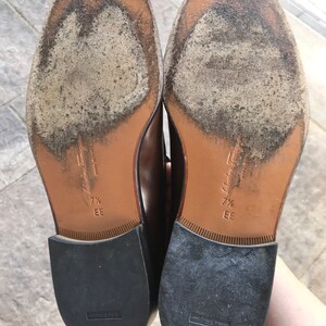 May include: A pair of brown leather shoes with black soles. The shoes are size 7 1/2 EE and are made in Italy.
