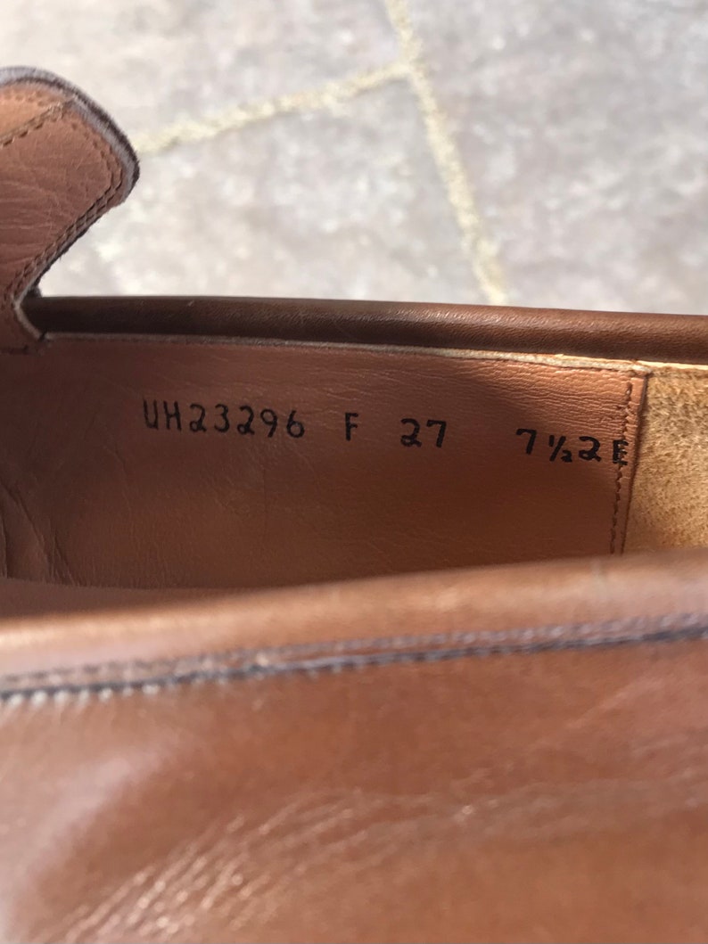May include: Close-up of the inside of a brown leather shoe with the size and style number printed on the insole. The text reads "UH23296 F 27 7 1/2 E".