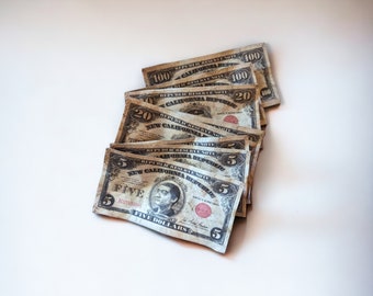 May include: A stack of old, worn, paper bills. The bills are from the "New California Republic" and are in denominations of $5, $20, and $100. The bills are faded and have a worn look.