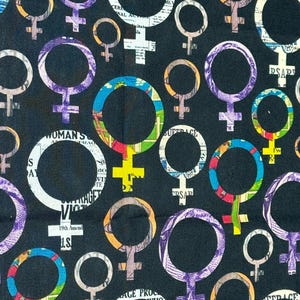 Può includere: Un tessuto nero con un motivo ripetuto di simboli femminili colorati e viola. I simboli sono riempiti di testo e immagini. Il testo include le parole "WOMAN'S", "SUFFRAGE", "PSAR" e "19th Amend".
