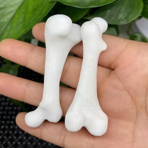 May include: Two white, bone-shaped, decorative items with a textured surface.