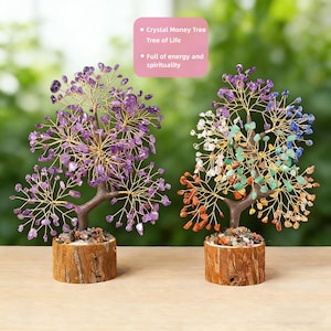 May include: Two crystal money trees, each with a wire tree design and gemstone leaves. One tree features purple amethyst, the other has a variety of colorful gemstones. Both trees sit on a wooden base with small stones.